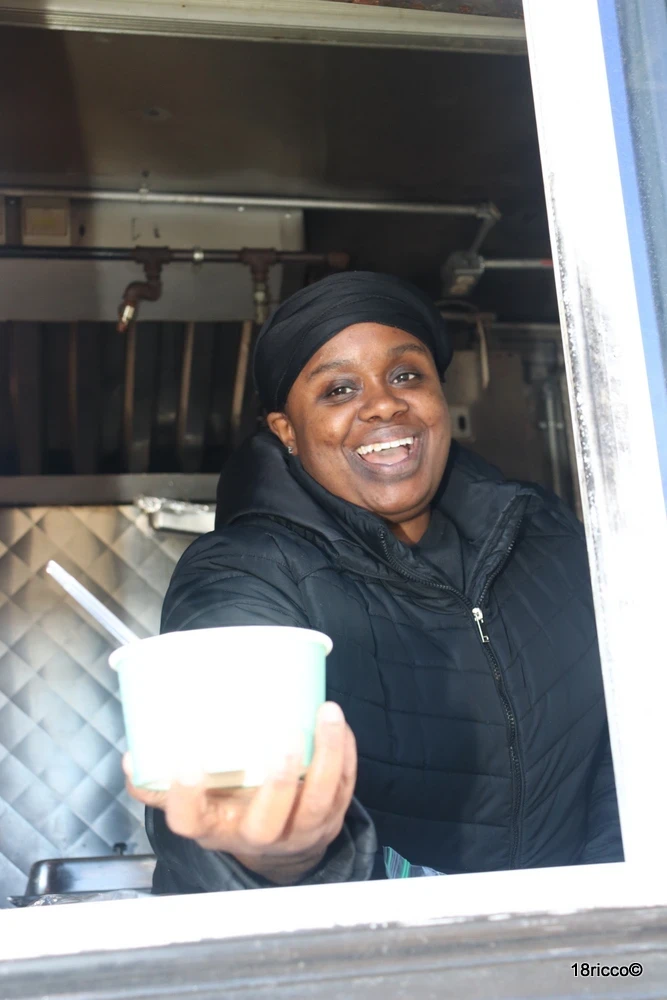 Foxy Fran's team member smiling and serving a warm dish through the food truck window